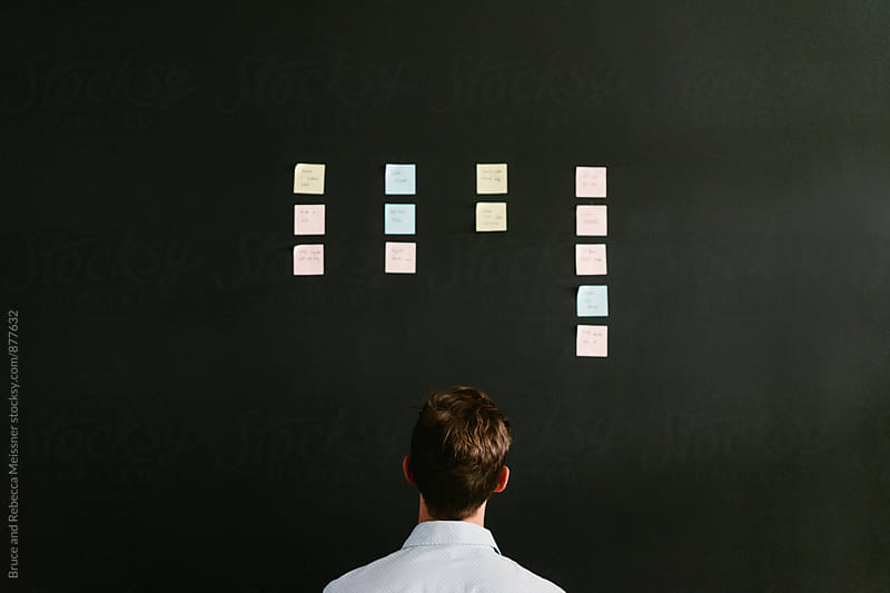 Photo of a man staring at PostIt notes on the wall